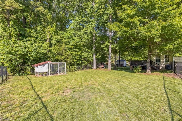 view of yard featuring exterior structure, an outdoor structure, and a wooden deck