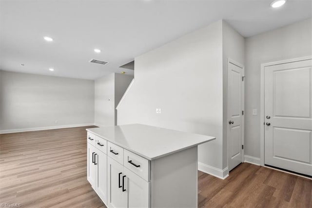 4196 Emmas Way E, Bend, NC 27018 - kitchen with light wood-type flooring, baseboards, white cabinetry, light countertops, and a kitchen island
