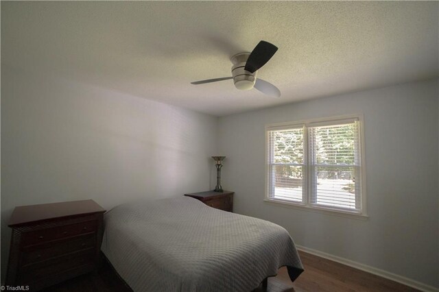 bedroom with wood finished floors, baseboards, ceiling fan, and a textured ceiling