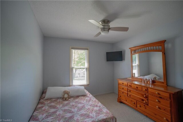 bedroom with light colored carpet, a textured ceiling, ceiling fan, and baseboards
