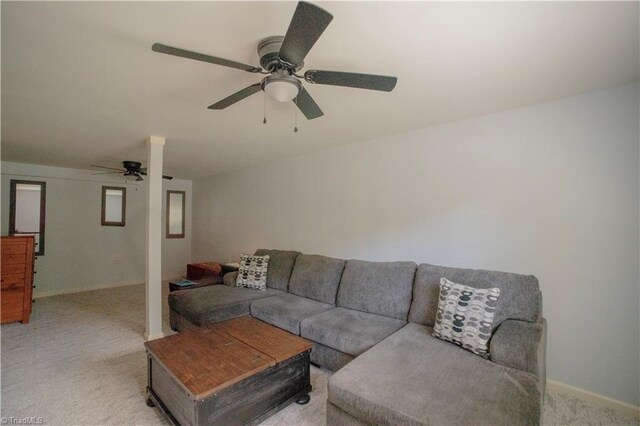 living room with light colored carpet, a ceiling fan, and baseboards