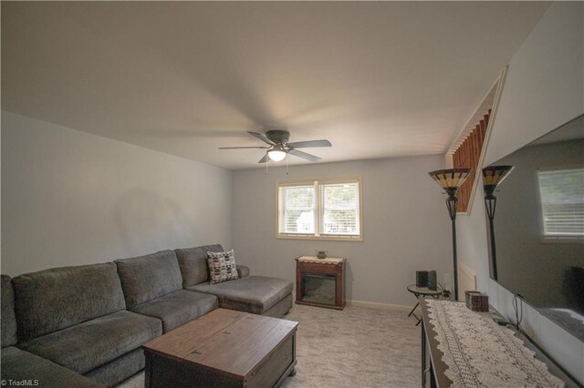 living room featuring light carpet, a ceiling fan, and baseboards