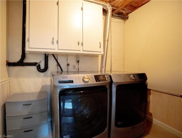 laundry room with cabinet space, washing machine and dryer, and a wainscoted wall