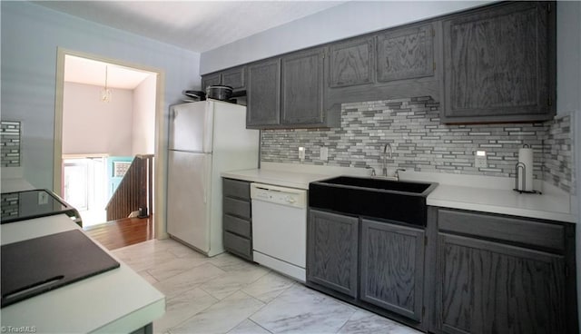 kitchen with white appliances, a sink, light marble finish floors, tasteful backsplash, and light countertops