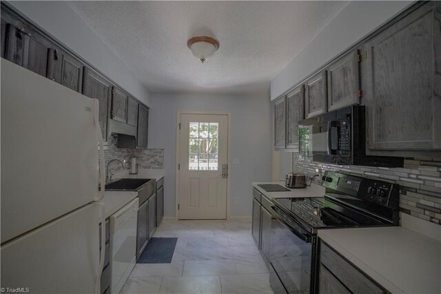 kitchen with black appliances, a sink, a textured ceiling, tasteful backsplash, and light countertops
