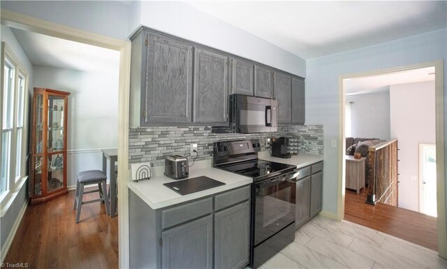 kitchen featuring black appliances, gray cabinetry, light countertops, and backsplash