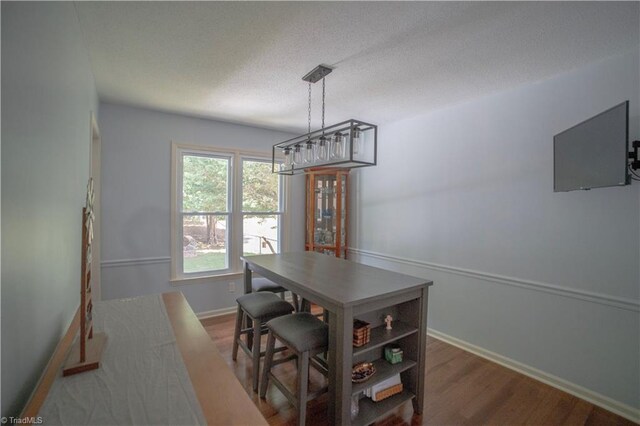 dining area with a textured ceiling, wood finished floors, and baseboards
