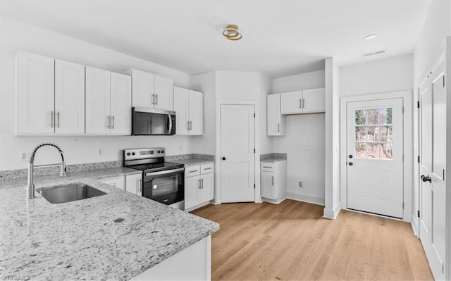 kitchen featuring appliances with stainless steel finishes, light stone counters, sink, light hardwood / wood-style floors, and white cabinetry