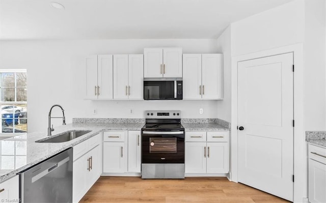 kitchen with white cabinetry, sink, light wood-type flooring, and appliances with stainless steel finishes