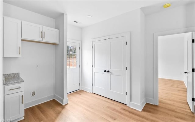 kitchen with white cabinets, light hardwood / wood-style floors, and light stone countertops