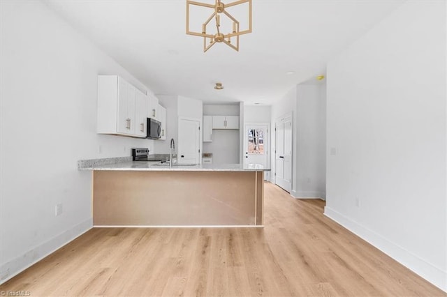 kitchen featuring sink, a notable chandelier, kitchen peninsula, white cabinets, and appliances with stainless steel finishes