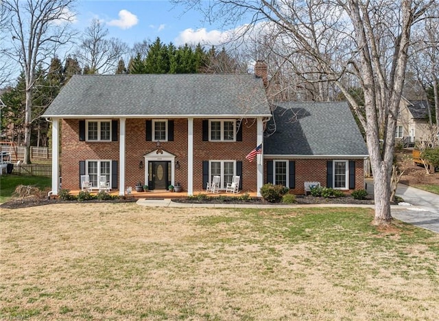 neoclassical / greek revival house with a front lawn, a chimney, and fence