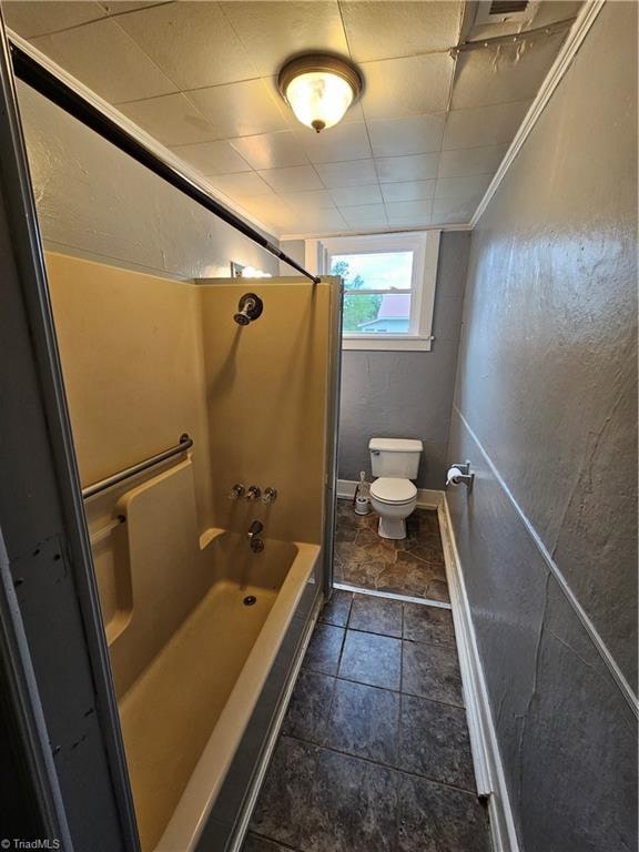 bathroom featuring bathtub / shower combination, toilet, crown molding, and tile patterned flooring