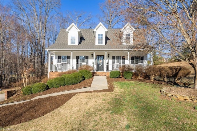 new england style home featuring a porch, a front lawn, and roof with shingles