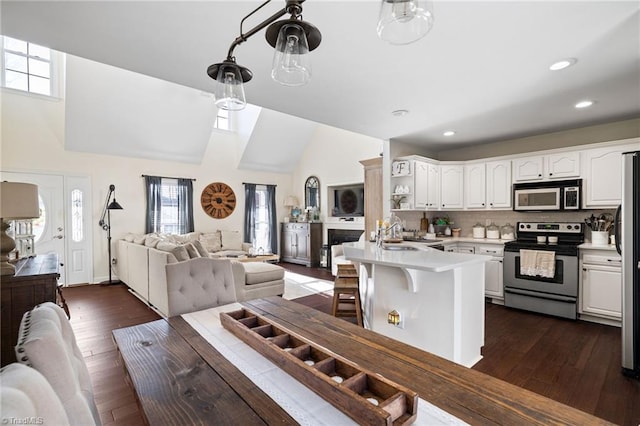 kitchen featuring a peninsula, light countertops, appliances with stainless steel finishes, white cabinetry, and open floor plan