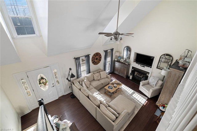 living area featuring plenty of natural light, high vaulted ceiling, ceiling fan, and dark wood-style flooring