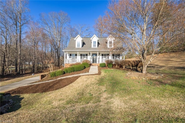 new england style home with a porch, a front lawn, and driveway