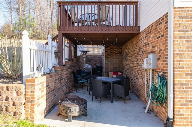 view of patio with a wooden deck, outdoor dining area, and an outdoor fire pit