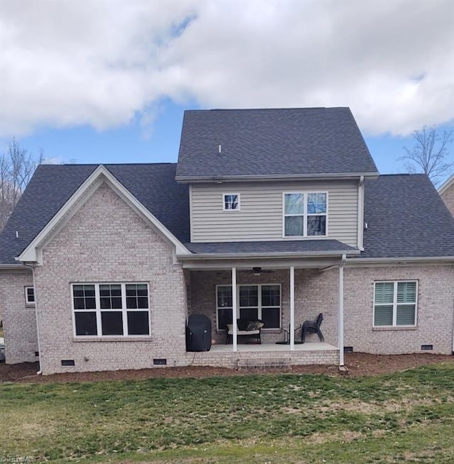 rear view of property featuring a patio, a lawn, brick siding, and crawl space