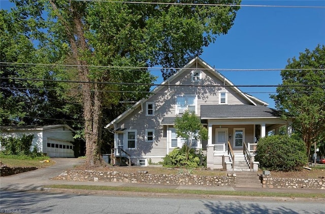 view of front of home featuring a detached garage, a porch, and an outbuilding