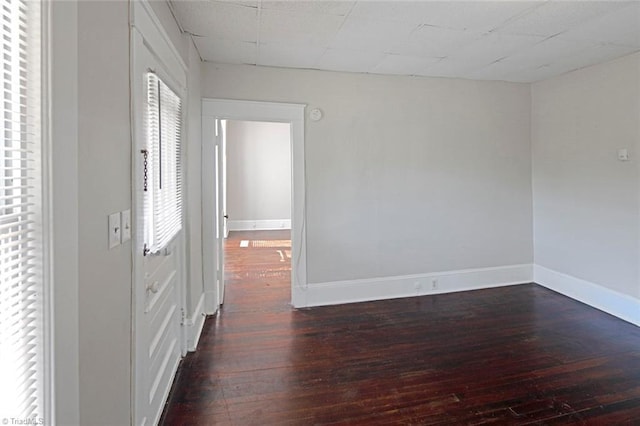 spare room with a paneled ceiling, baseboards, and hardwood / wood-style floors