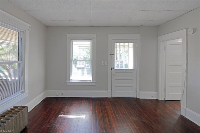 foyer with dark wood-style flooring, baseboards, a drop ceiling, and radiator heating unit