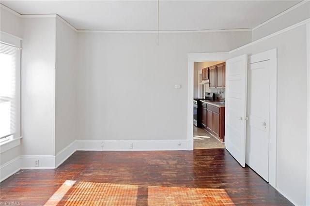 spare room featuring crown molding, baseboards, and wood finished floors