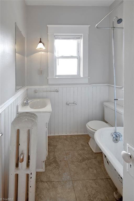 bathroom featuring wainscoting, a bathing tub, and toilet