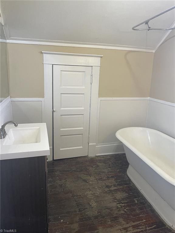 full bath with wainscoting, a soaking tub, wood finished floors, and vanity