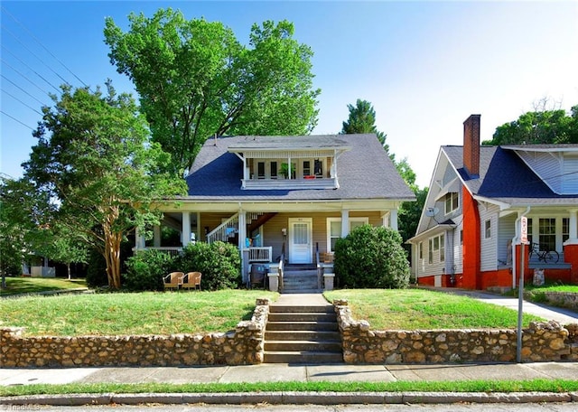 view of front facade with covered porch, a front lawn, and stairs