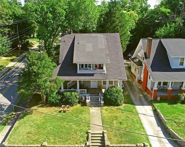 view of front of home featuring roof with shingles, stairway, a porch, and a front yard