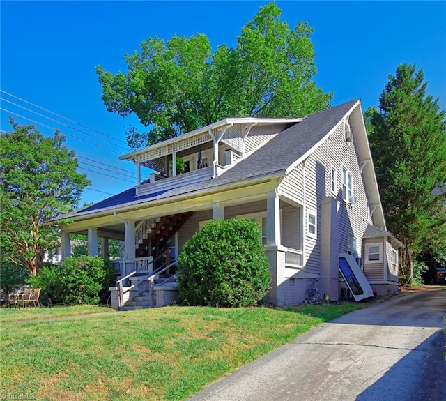 bungalow with covered porch, a shingled roof, and a front yard