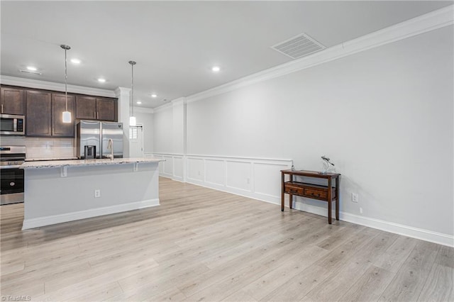 kitchen with a breakfast bar area, backsplash, stainless steel appliances, dark brown cabinetry, and a center island with sink