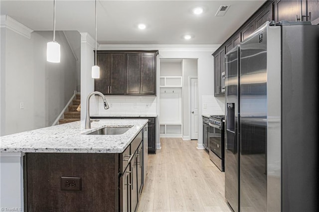 kitchen featuring pendant lighting, sink, appliances with stainless steel finishes, a kitchen island with sink, and dark brown cabinets