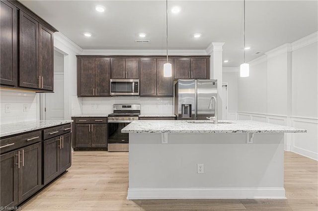 kitchen featuring stainless steel appliances, an island with sink, hanging light fixtures, and dark brown cabinetry