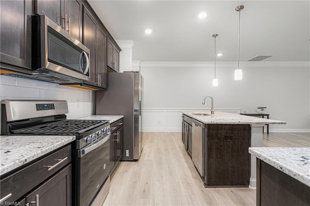 kitchen featuring sink, dark brown cabinets, stainless steel appliances, light stone countertops, and decorative light fixtures