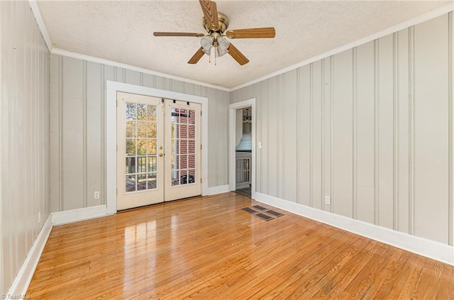 empty room featuring french doors, light hardwood / wood-style floors, ceiling fan, and ornamental molding