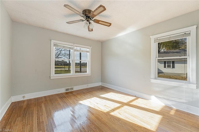 spare room with ceiling fan, plenty of natural light, wood-type flooring, and a textured ceiling