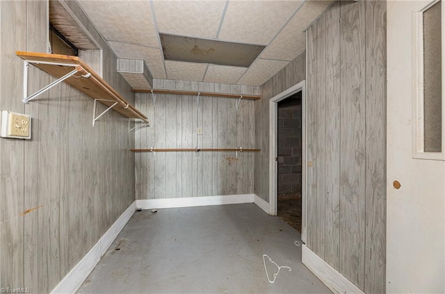 basement featuring a paneled ceiling and wooden walls