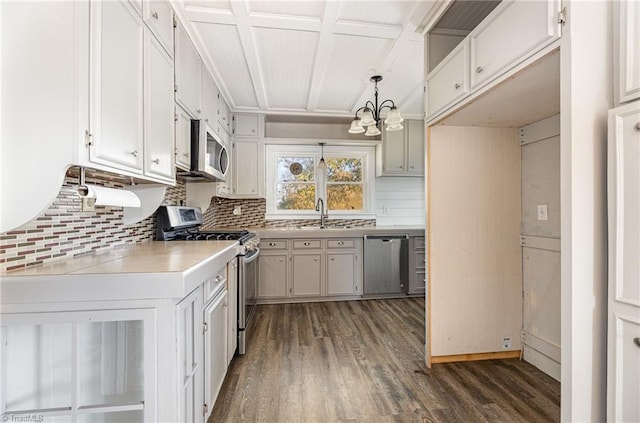 kitchen with pendant lighting, backsplash, dark wood-type flooring, stainless steel appliances, and a chandelier