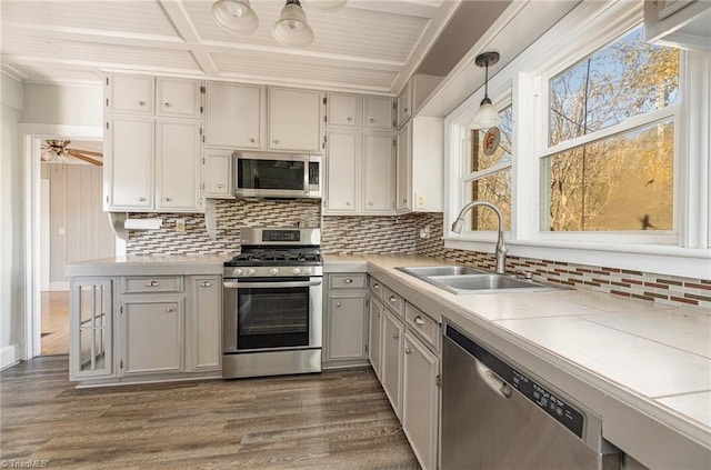 kitchen featuring tasteful backsplash, dark wood-type flooring, hanging light fixtures, and appliances with stainless steel finishes