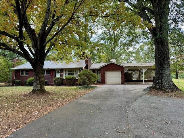 ranch-style house featuring an attached garage, driveway, a chimney, an attached carport, and brick siding
