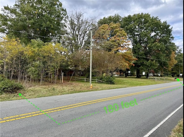 view of asphalt street featuring view of wooded area
