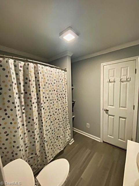 bathroom featuring baseboards, a shower with curtain, toilet, crown molding, and wood finished floors