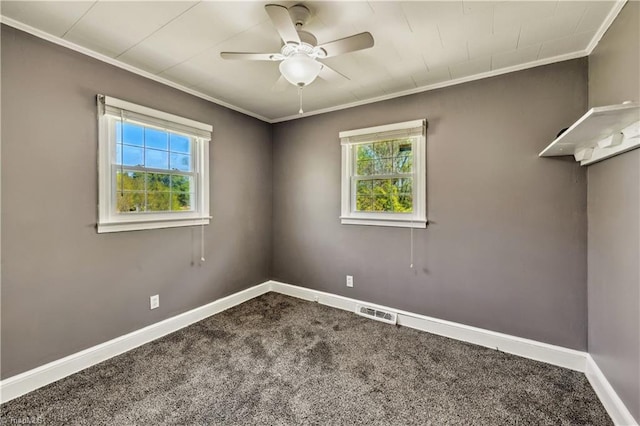 carpeted spare room with ceiling fan, baseboards, ornamental molding, and a healthy amount of sunlight