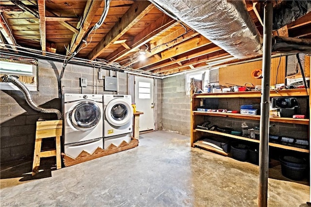 below grade area with concrete block wall and washer and clothes dryer