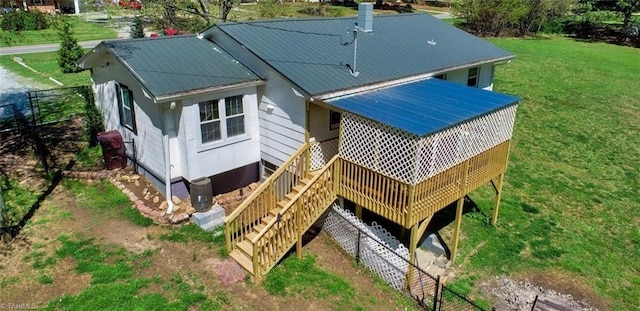 back of property featuring stairway, metal roof, and a lawn