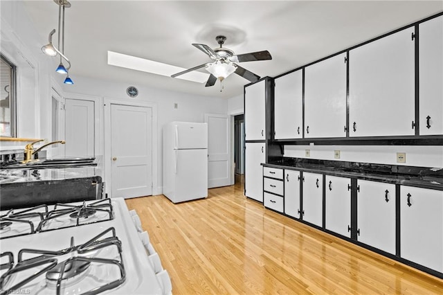 kitchen with sink, a skylight, white cabinetry, light wood-type flooring, and white appliances