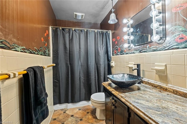 bathroom featuring toilet, vanity, tile patterned floors, and tile walls