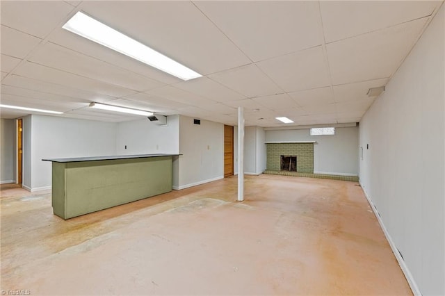 basement with a brick fireplace and a drop ceiling